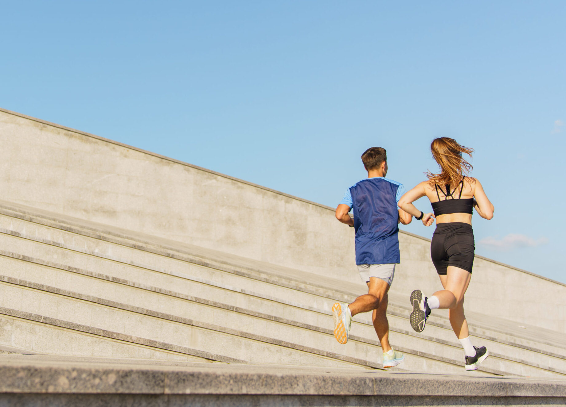 Runners Embrace the Sunlit Day as They Sprint up Modern Steps in an Urban Landscape During Morning Exercise